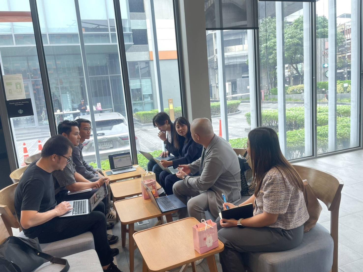 窓際の席で資料を広げ、話し合う人たち